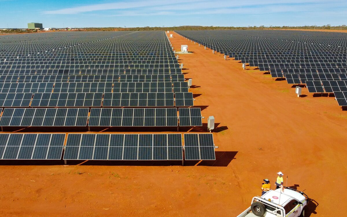 Rows of solar panels at the Gruyere microgrid in the Western Australian Goldfields, red iron-rich earth between the rows.
